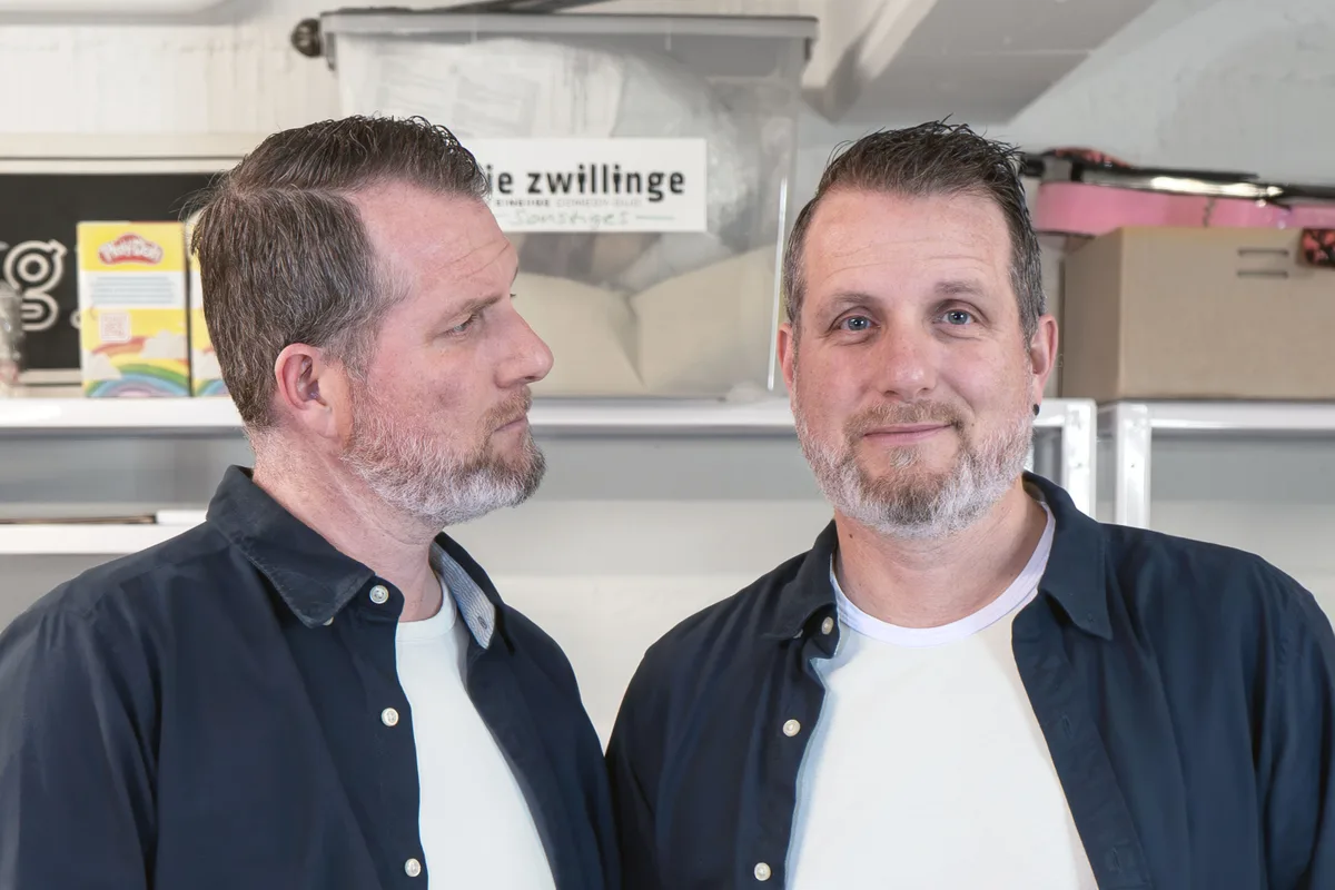 Auflösung: Links ist Matthias und rechts Roland Portmann Matthias Portmann blickt auf Roland Portmann, der direkt in die Kamera schaut.